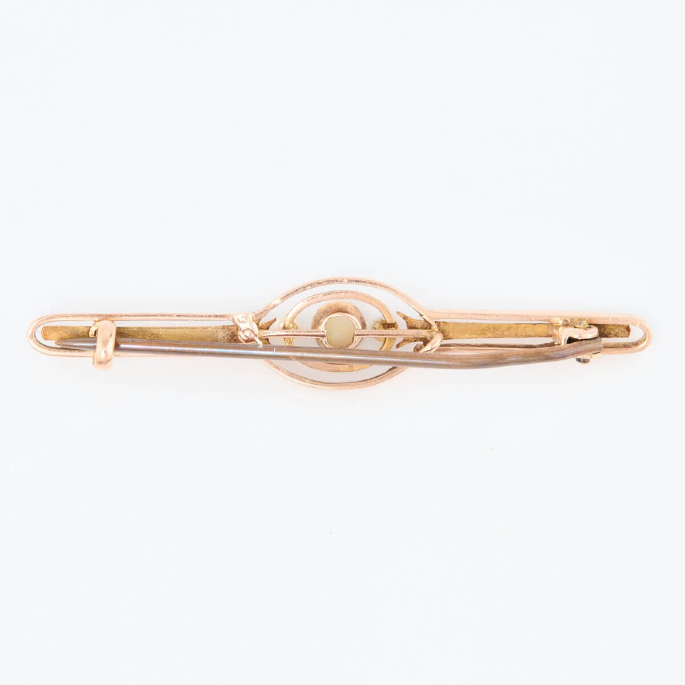 A 9ct gold bar brooch featuring a central cabochon opal flanked by two small seed pearls within an openwork oval motif. View III