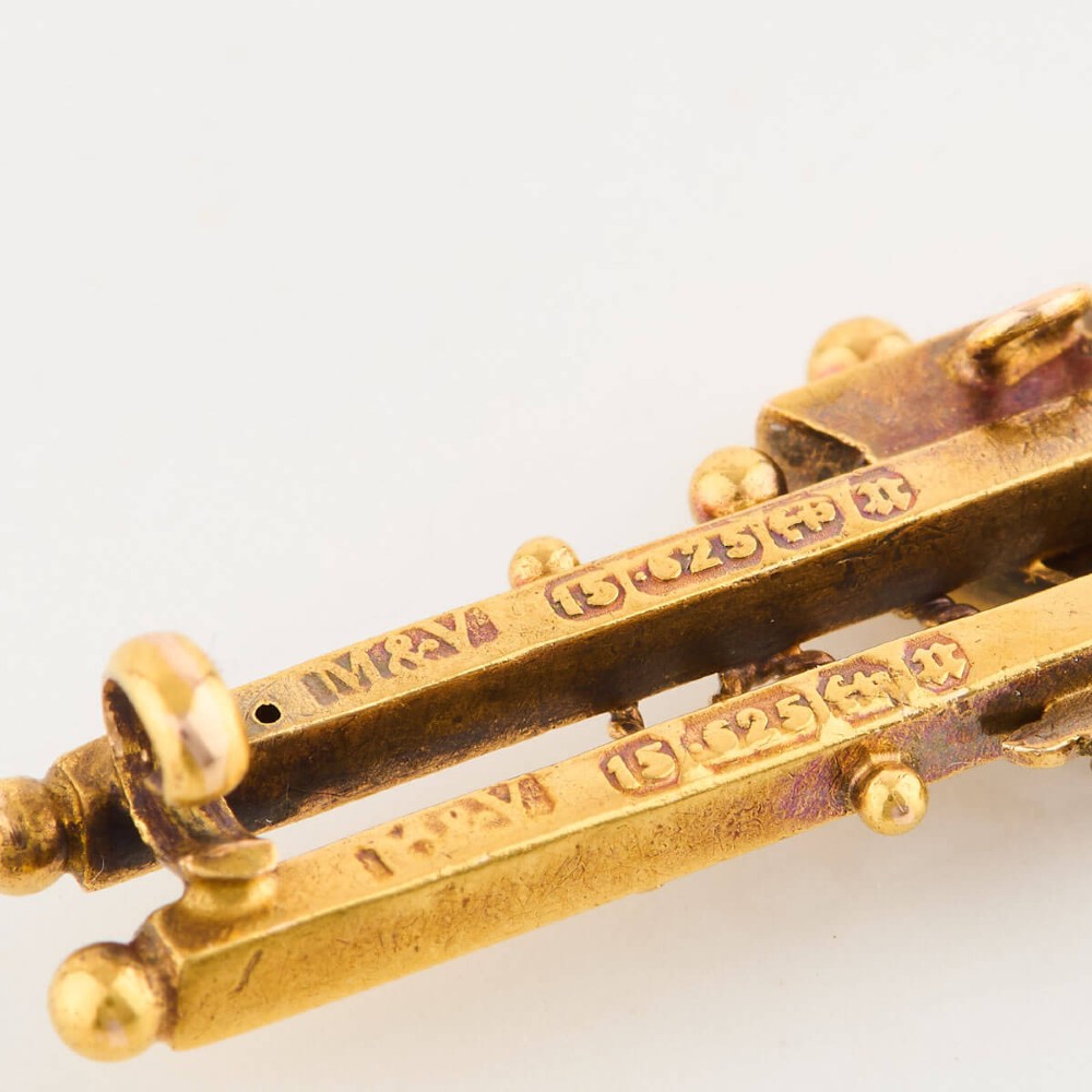 A late Victorian 15ct gold double bar brooch featuring a central lozenge setting with a round blue sapphire flanked by two pearls, decorated with rope-twist wirework and ball finials. View VII