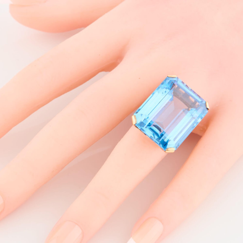 A 9ct gold vintage dress ring featuring a large emerald-cut light blue paste stone held in a raised basket setting. View II
