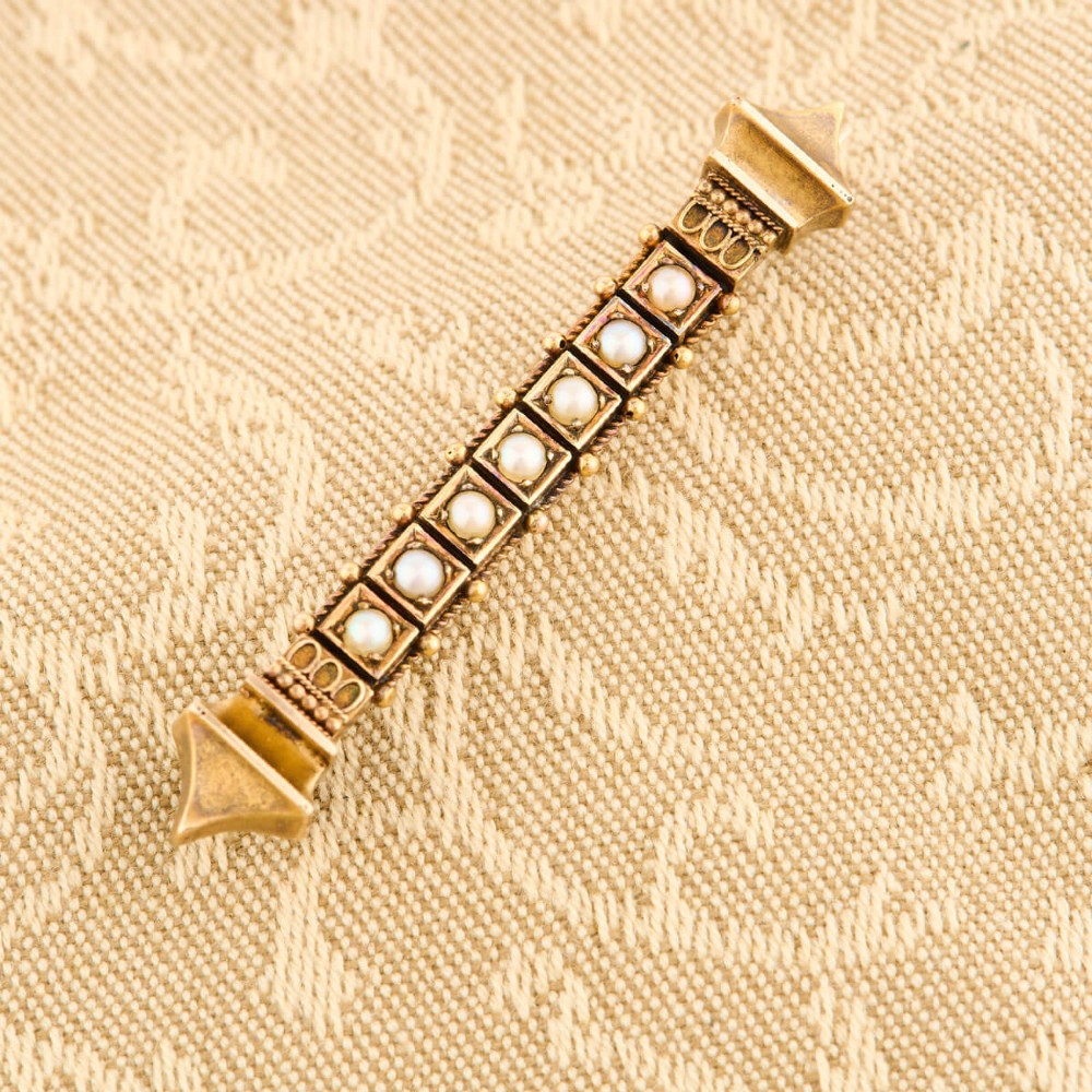 An 18ct yellow gold bar brooch decorated with a row of pearls, beaded borders, and architectural finials. View II