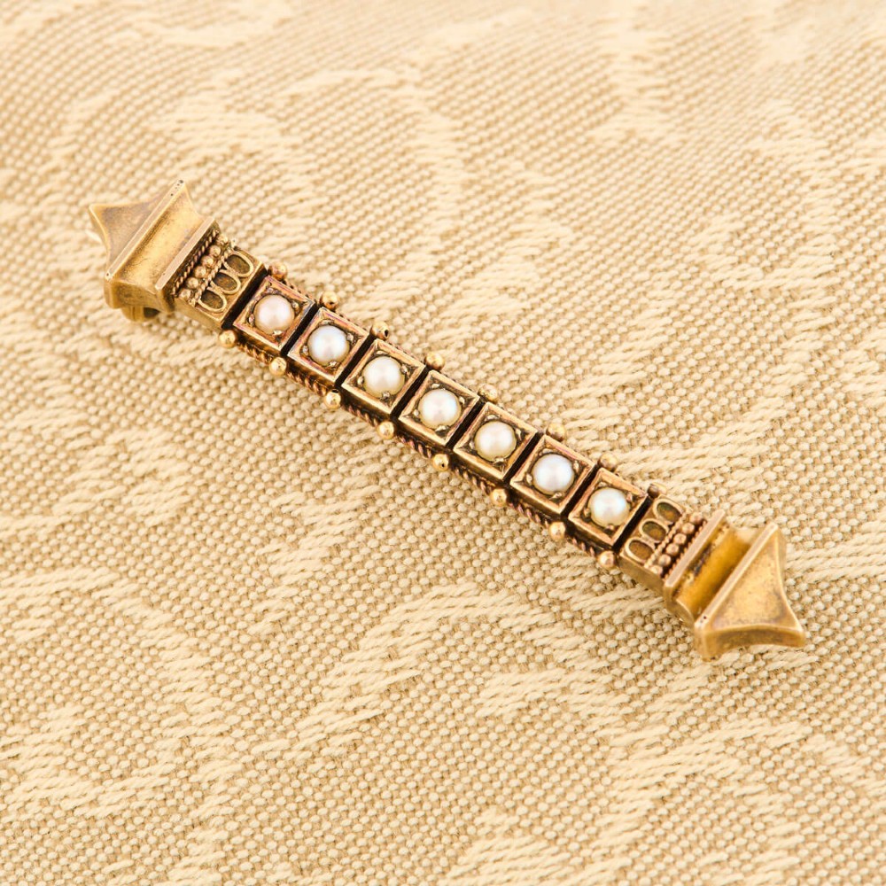 An 18ct yellow gold bar brooch decorated with a row of pearls, beaded borders, and architectural finials. View III