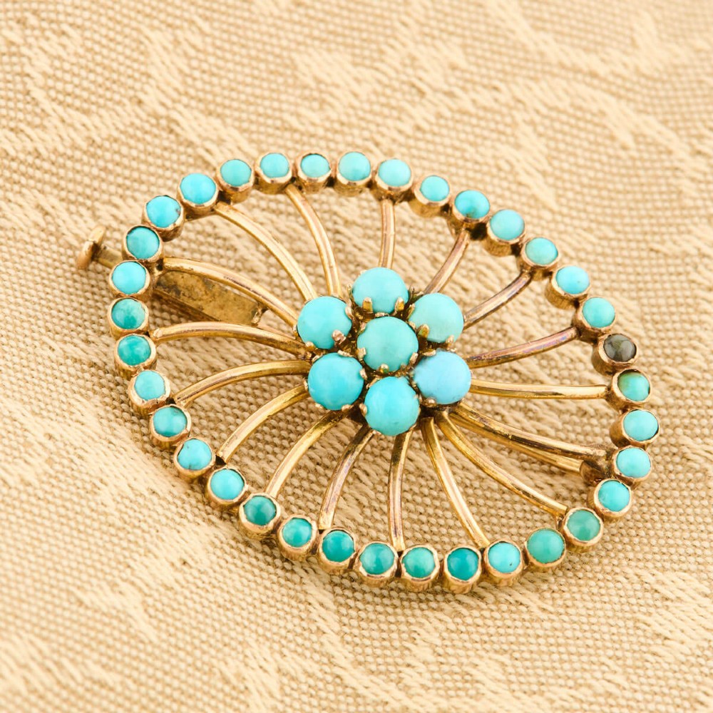 An oval openwork 14ct yellow gold brooch featuring a central floral turquoise cluster, radiating spokes, and a perimeter border set with round turquoise cabochons. View II