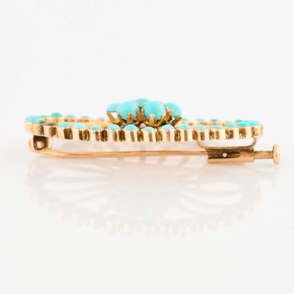 An oval openwork 14ct yellow gold brooch featuring a central floral turquoise cluster, radiating spokes, and a perimeter border set with round turquoise cabochons. View V
