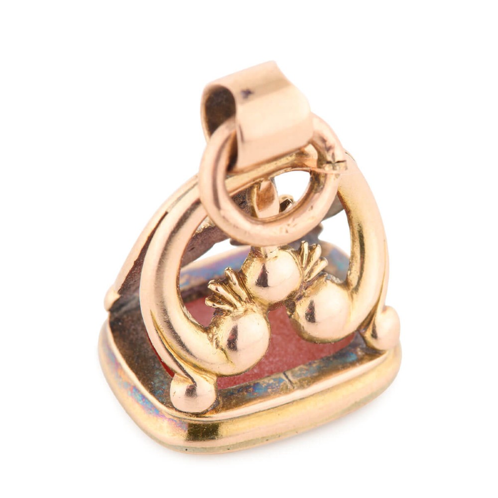 An antique 9ct gold wax seal fob featuring a curved mount and a carnelian base stone.