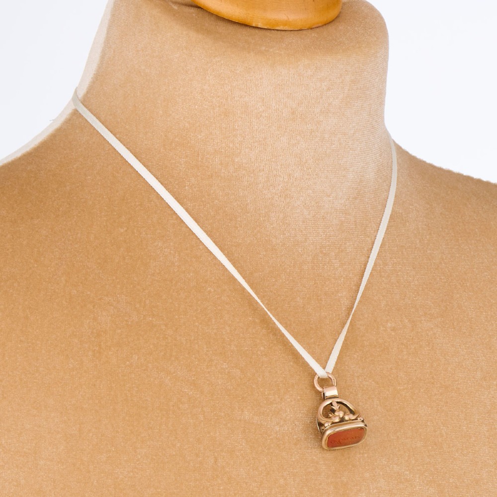 An antique 9ct gold wax seal fob featuring a curved mount and a carnelian base stone. View IV