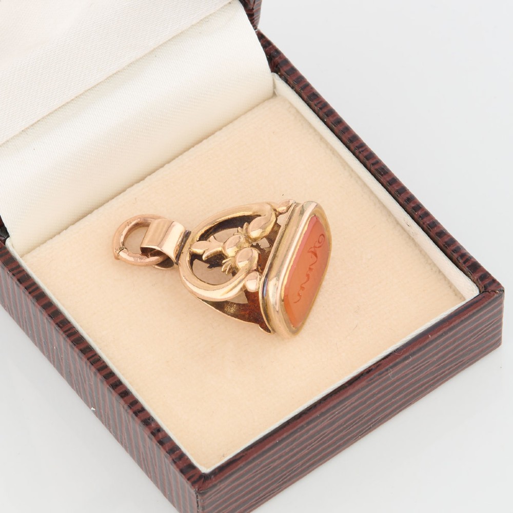 An antique 9ct gold wax seal fob featuring a curved mount and a carnelian base stone. View V