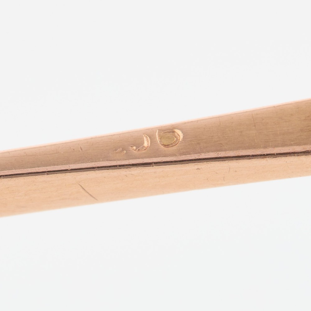 A 9ct yellow gold horizontal bar brooch with a central emerald-cut blue paste stone and an attached safety chain. View VI