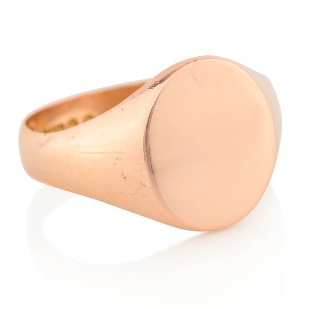 An unengraved 9ct rose gold oval signet ring featuring a polished flat face and thick band.