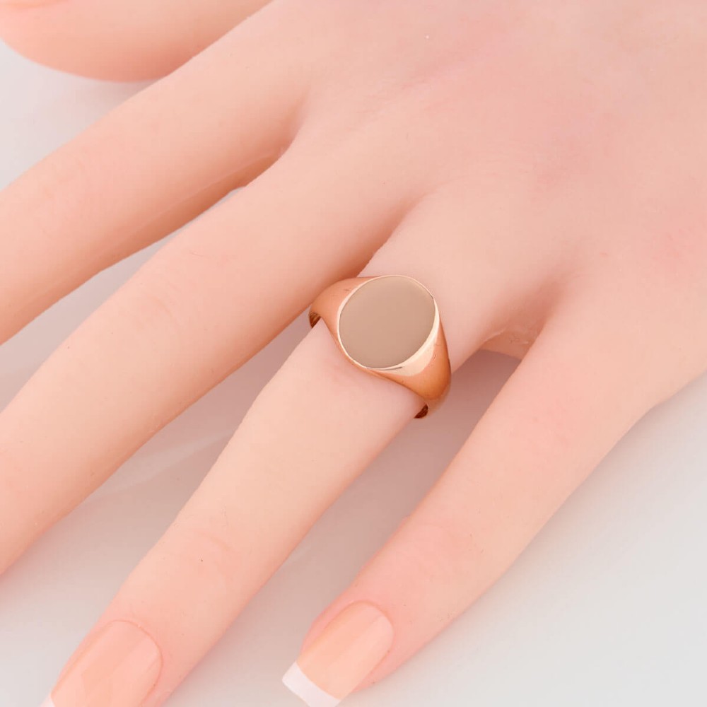An unengraved 9ct rose gold oval signet ring featuring a polished flat face and thick band. View II