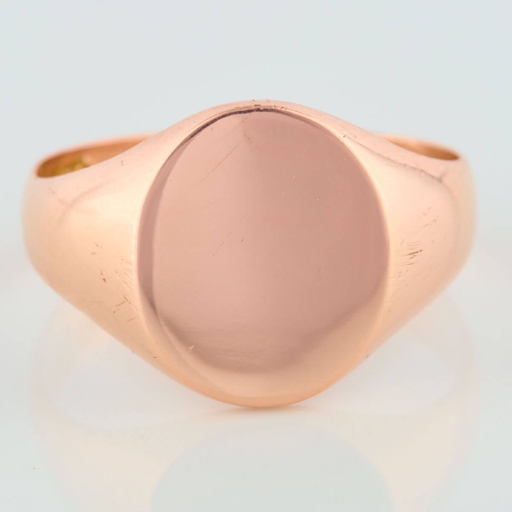 An unengraved 9ct rose gold oval signet ring featuring a polished flat face and thick band. View III