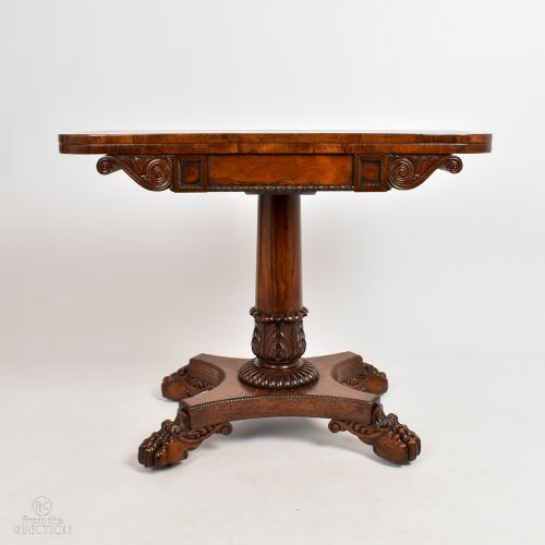 fig 2. A William IV rosewood fold-top card table featuring a rectangular swivel top, carved pedestal, and a quadform base with carved feet.