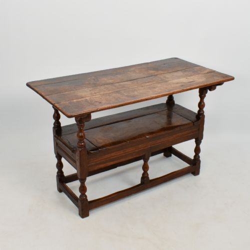 fig 1. An 18th-century dark oak monks bench featuring a convertible tilt-top backrest, turned arm supports, and block legs with perimeter stretchers.