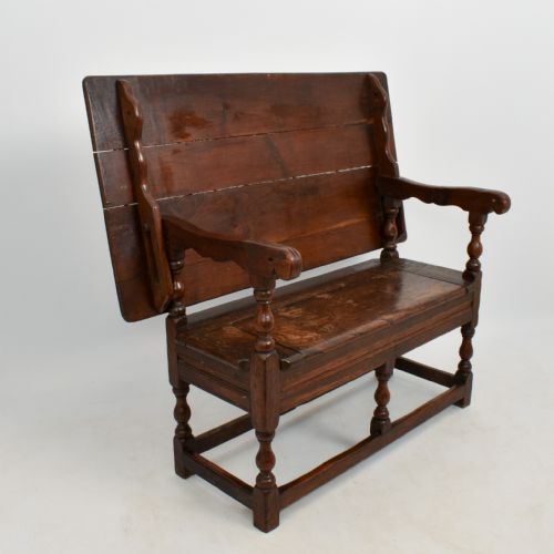 fig 3. An 18th-century dark oak monks bench featuring a convertible tilt-top backrest, turned arm supports, and block legs with perimeter stretchers.