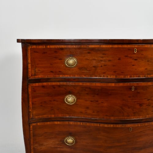 fig 1. An eighteenth-century George III serpentine-fronted mahogany chest of drawers with three drawers, circular brass ring handles, and splayed bracket feet.