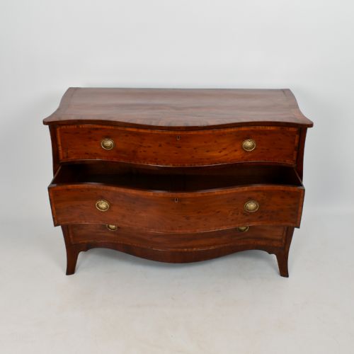 fig 2. An eighteenth-century George III serpentine-fronted mahogany chest of drawers with three drawers, circular brass ring handles, and splayed bracket feet.
