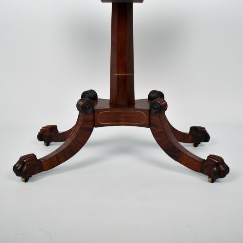 fig 3. A William IV rosewood fold-over tea table featuring a rectangular hinged top, brass inlaid apron, and a central pedestal resting on four carved splayed legs with brass castors.