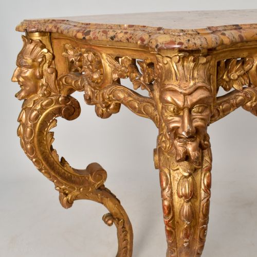 fig 1. A 19th-century giltwood console table featuring carved grotesque masks, central shell carving, and a pink and beige marble top.