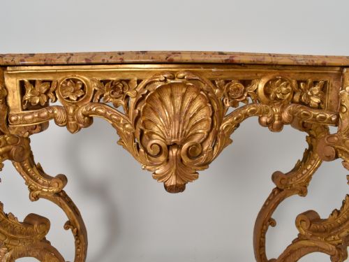 fig 3. A 19th-century giltwood console table featuring carved grotesque masks, central shell carving, and a pink and beige marble top.