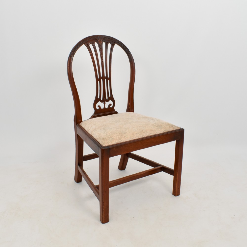 An 18th-century mahogany dining chair featuring an arched back with carved splat, square legs, structural stretchers, and a patterned cloth seat.