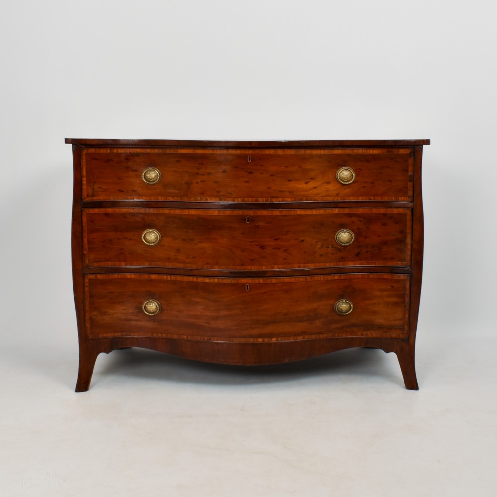 An eighteenth-century George III serpentine-fronted mahogany chest of drawers with three drawers, circular brass ring handles, and splayed bracket feet.