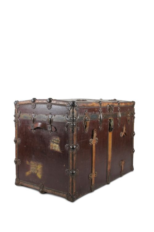fig 2. An antique French dark brown leather trunk with metal corner guards, riveted details, central latches, and vertical leather straps.