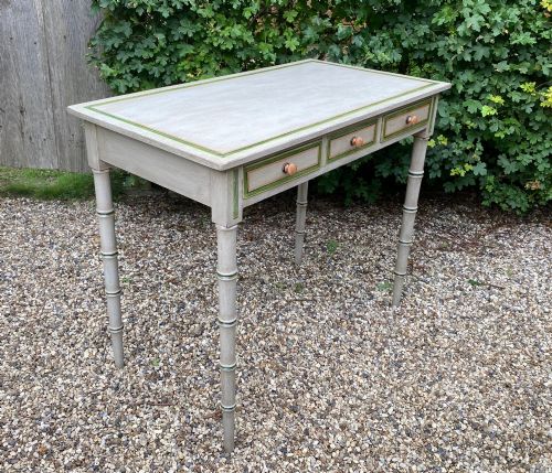 fig 1. A light grey painted Regency side table featuring green border lining, three drawers with turned wooden knobs, and four legs shaped like bamboo.