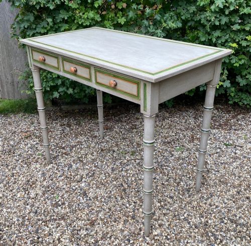 fig 2. A light grey painted Regency side table featuring green border lining, three drawers with turned wooden knobs, and four legs shaped like bamboo.