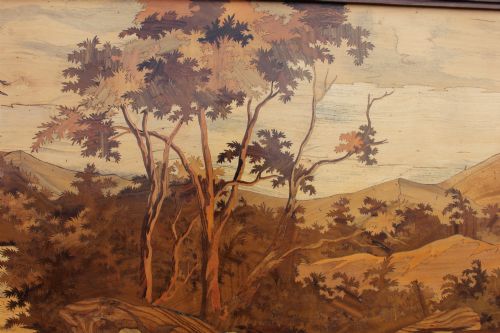 fig 2. A horizontal framed wooden marquetry panel depicting a herd of elephants bathing in a river surrounded by trees and mountains made from contrasting timber veneers.