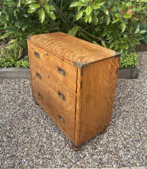 fig 1. A mid-19th-century satin birch military campaign chest featuring three full-width drawers with flush recessed brass handles and corner brass protective brackets.