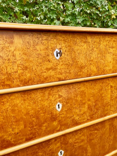 fig 3. A mid-19th-century Swedish satin birch chest featuring four horizontal straight drawers with diamond-shaped white keyhole escutcheons.