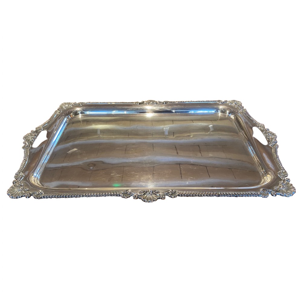 A rectangular silver plated tray with gadrooned edge detailing, shell corner motifs, and integrated handles.