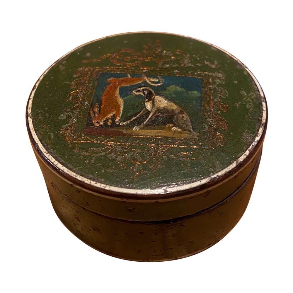 A circular Georgian papier-mache snuff box featuring a green lacquered lid decorated with a hand-painted scene of a dog and hare within a gilt border.