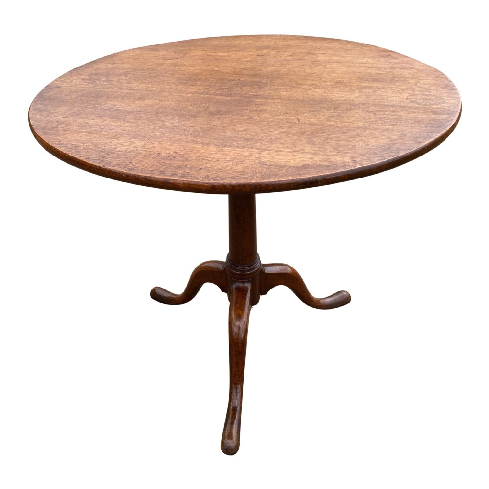 An antique Georgian circular oak tripod table with a central pillar and three curving cabriole legs.