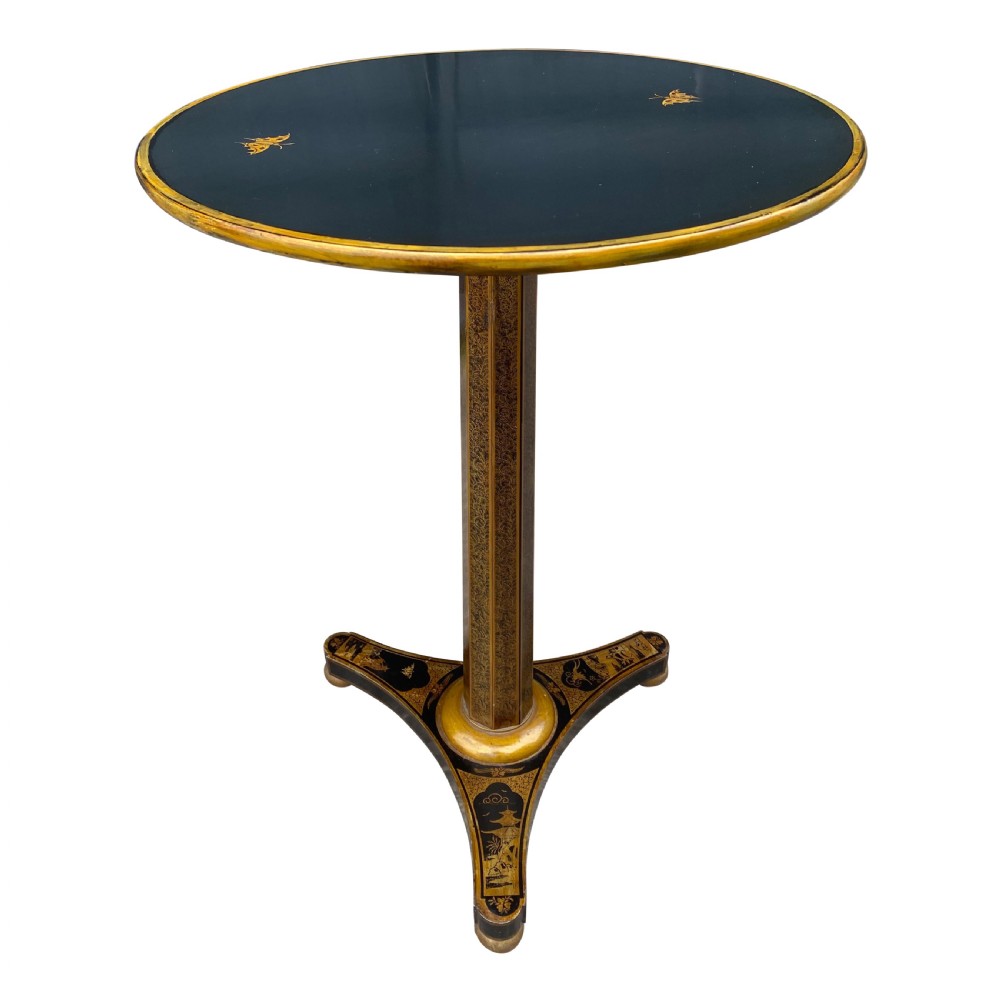 An antique circular black lacquer lamp table featuring intricate hand-painted gold chinoiserie motifs on a single pedestal with three splayed feet.