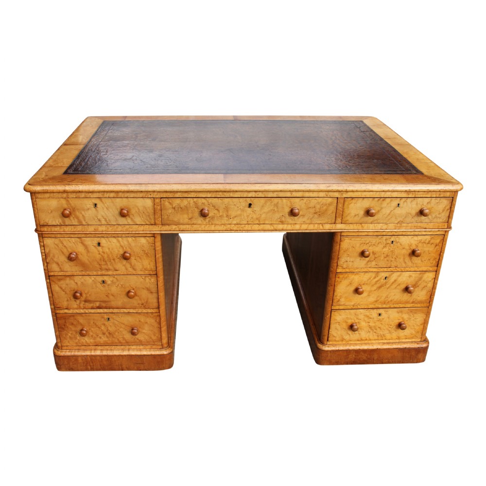 A nineteenth-century birds eye maple partners desk featuring a dark leather inset top and multiple pedestals of drawers with wooden knobs.