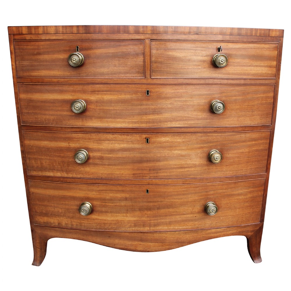 An early 19th-century mahogany bow fronted chest of drawers featuring two short upper drawers above three graduated long drawers with circular brass pulls.