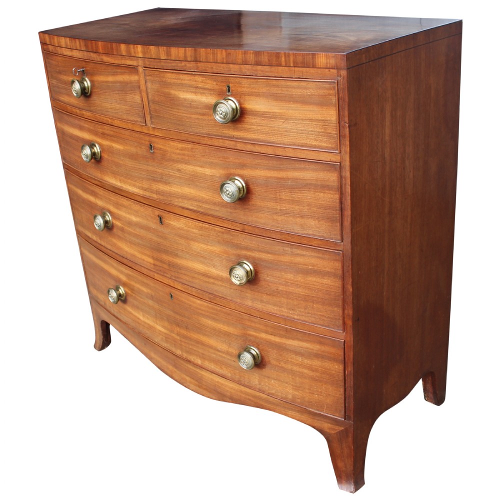 An early 19th-century mahogany bow fronted chest of drawers featuring two short upper drawers above three graduated long drawers with circular brass pulls. View II