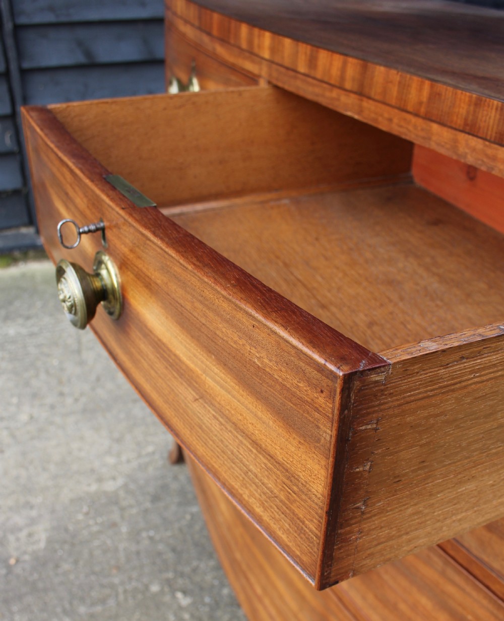 An early 19th-century mahogany bow fronted chest of drawers featuring two short upper drawers above three graduated long drawers with circular brass pulls. View IV