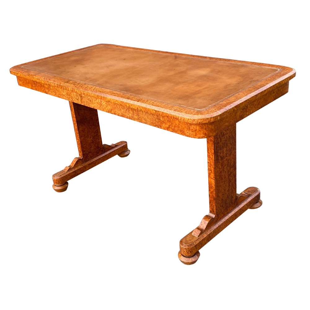 A nineteenth-century rectangular amboyna writing table featuring a brown leather inset top and dual trestle supports.