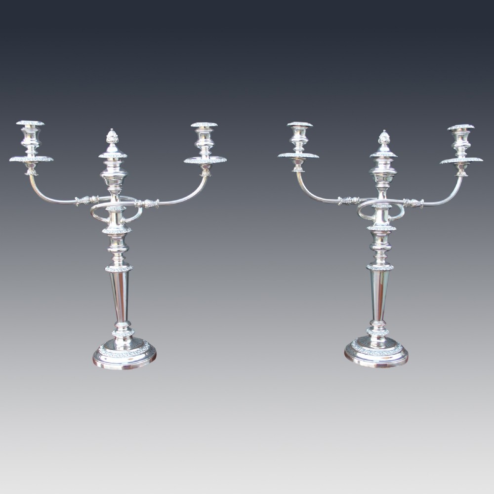 A set of four matching nineteenth-century Sheffield plate candelabras and candlesticks featuring polished silver finishes and classical tiered bases. View II