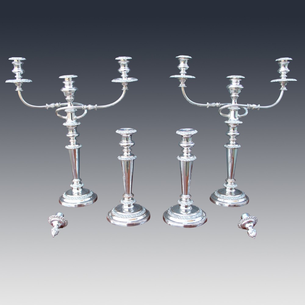 A set of four matching nineteenth-century Sheffield plate candelabras and candlesticks featuring polished silver finishes and classical tiered bases. View IV
