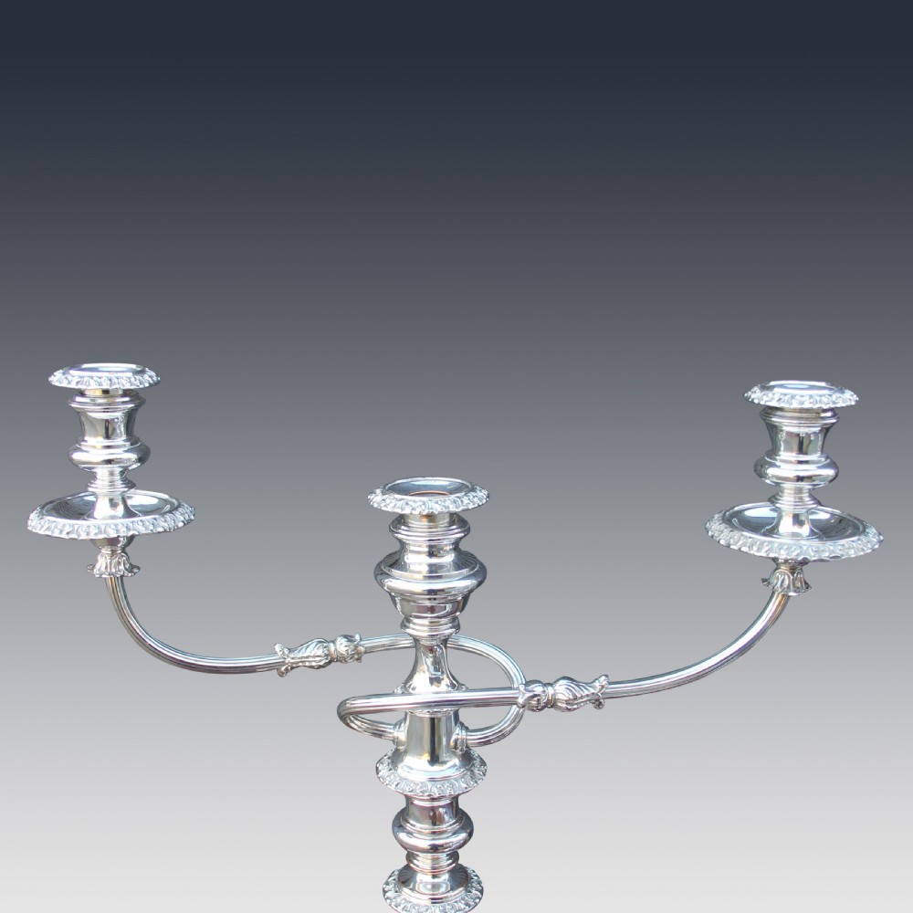 A set of four matching nineteenth-century Sheffield plate candelabras and candlesticks featuring polished silver finishes and classical tiered bases. View V