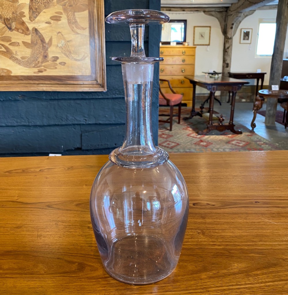 A clear hand-blown glass cider decanter with a bulbous body, a tapered neck with a raised collar ring, and a flat disc-shaped stopper.