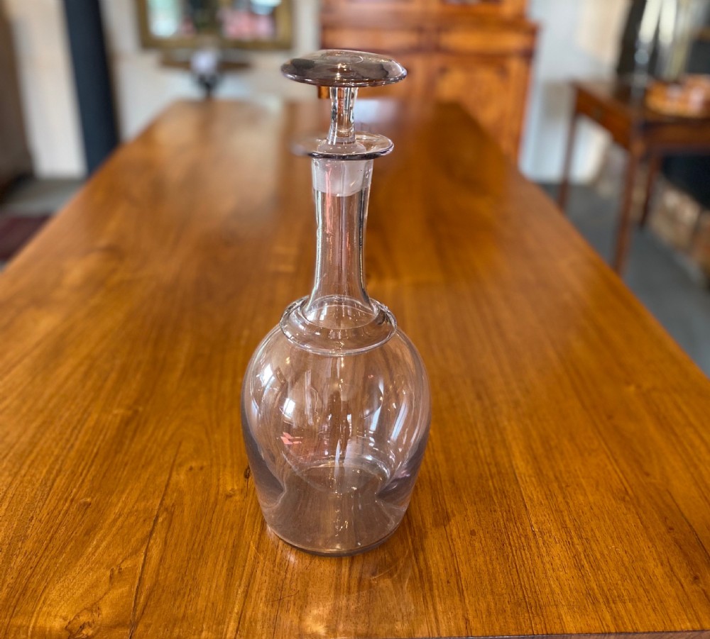 A clear hand-blown glass cider decanter with a bulbous body, a tapered neck with a raised collar ring, and a flat disc-shaped stopper. View II