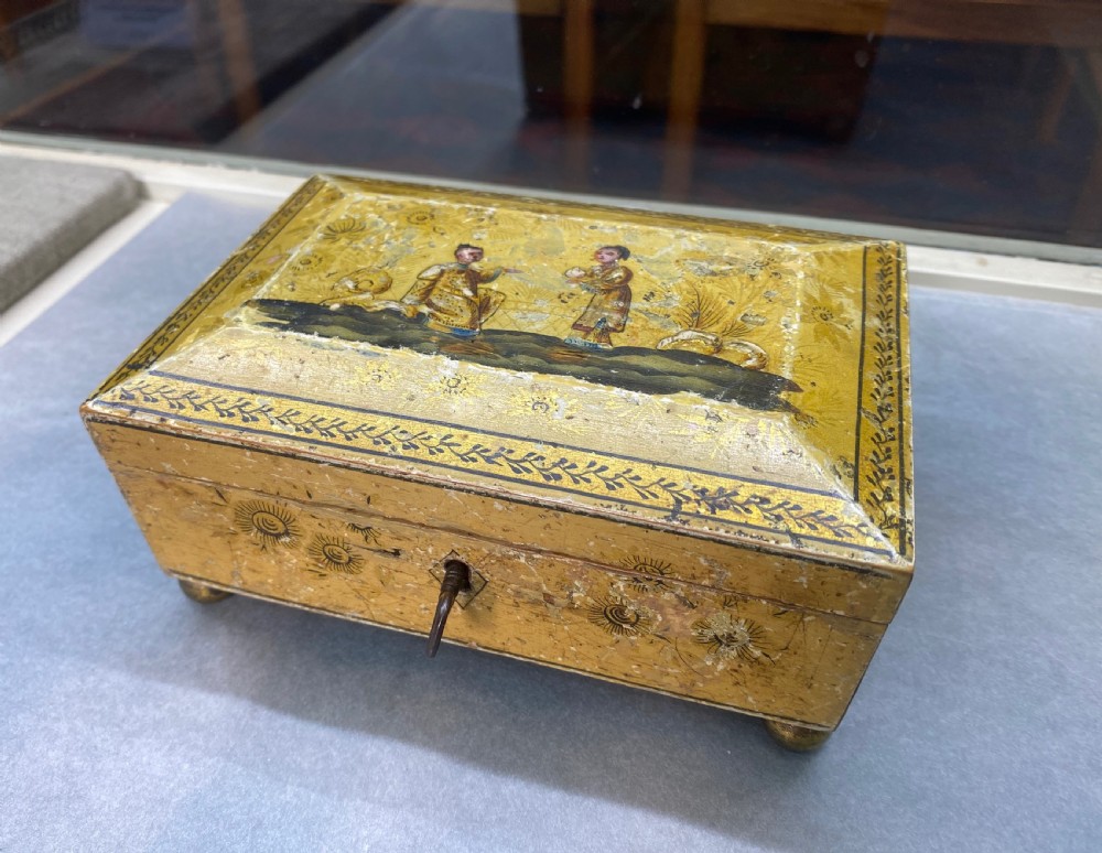 A rectangular yellow Georgian lacquer box adorned with hand-painted chinoiserie figures on the hinged lid and elevated on small ball feet.