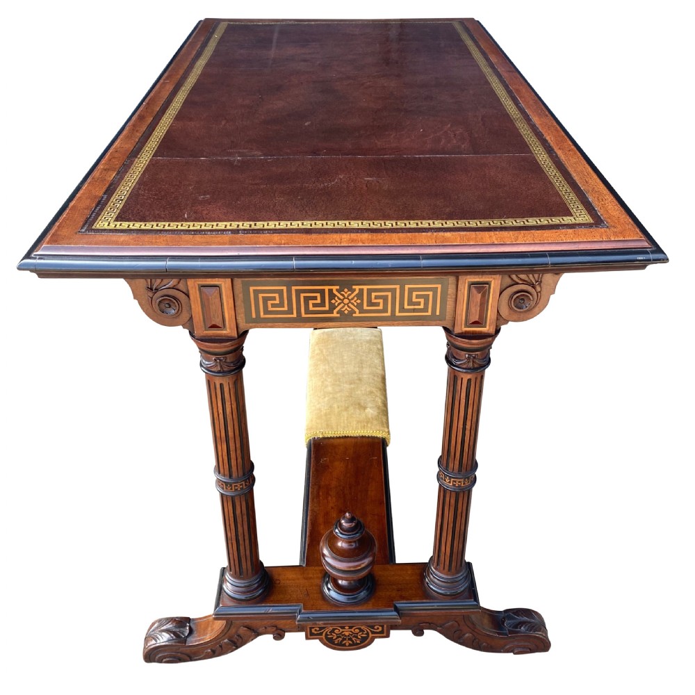 Late nineteenth-century mahogany writing table featuring a dark brown leather inset top with gilded tooling, fluted legs, and a central velvet-padded footrest on a low stretcher. View VI