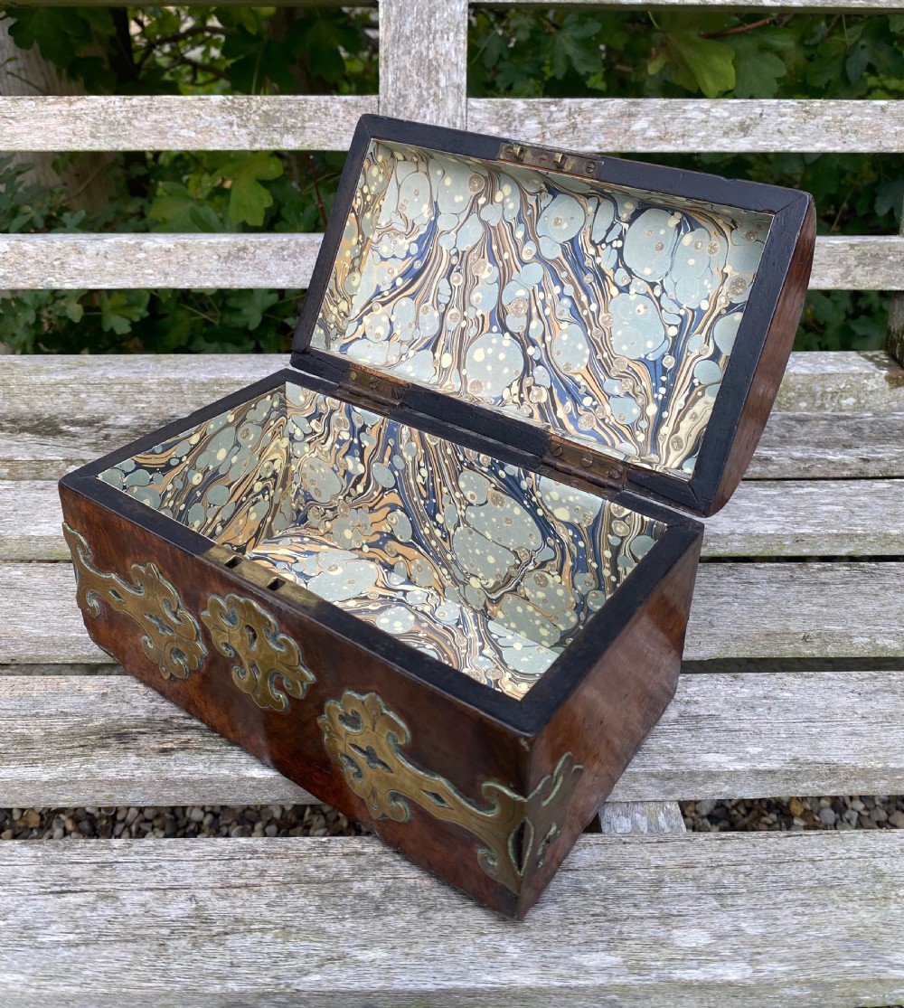 A 19th-century domed amboyna burr wood box featuring decorative brass strapwork mounts and corner fittings. View VI