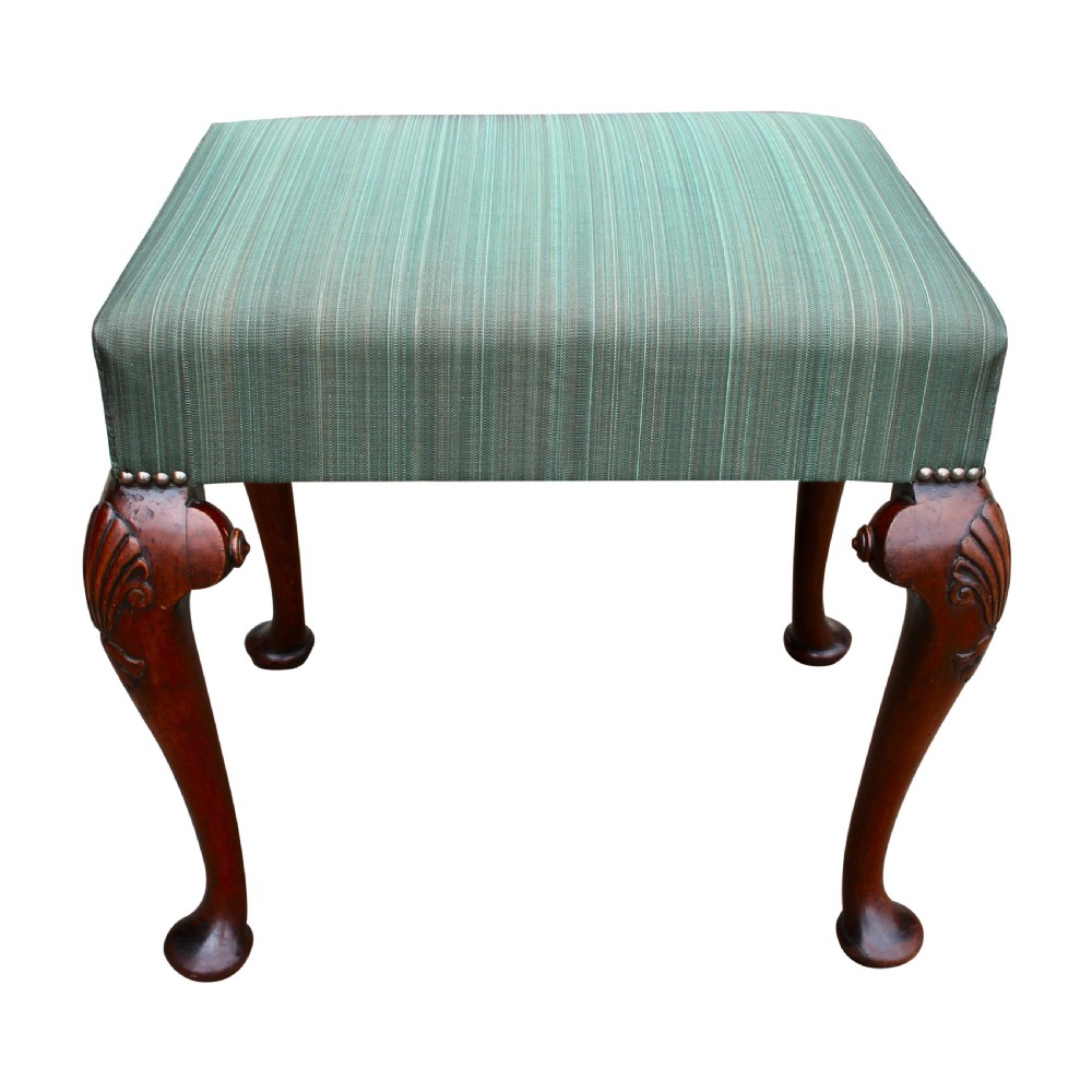 A 19th-century solid walnut stool featuring carved shell cabriole legs, pad feet, and a green striped fabric padded seat secured with brass studs. View II