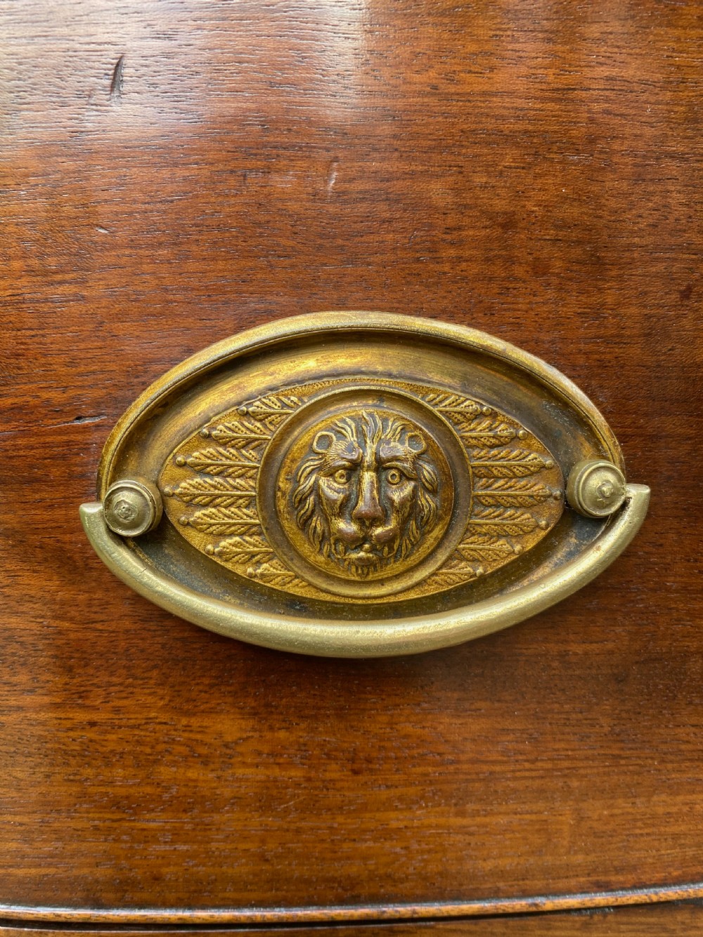 An early nineteenth-century mahogany bow-fronted chest of drawers featuring satinwood crossbanding, three graduated drawers, and oval brass handles. View VIII