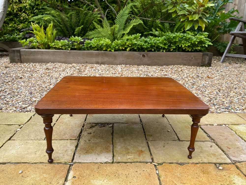 A low mahogany bed tray table featuring a rectangular flat top and four short turned legs.